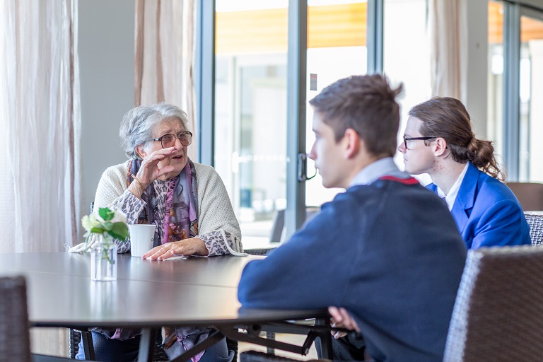 Two students speaking with an elderly woman.
